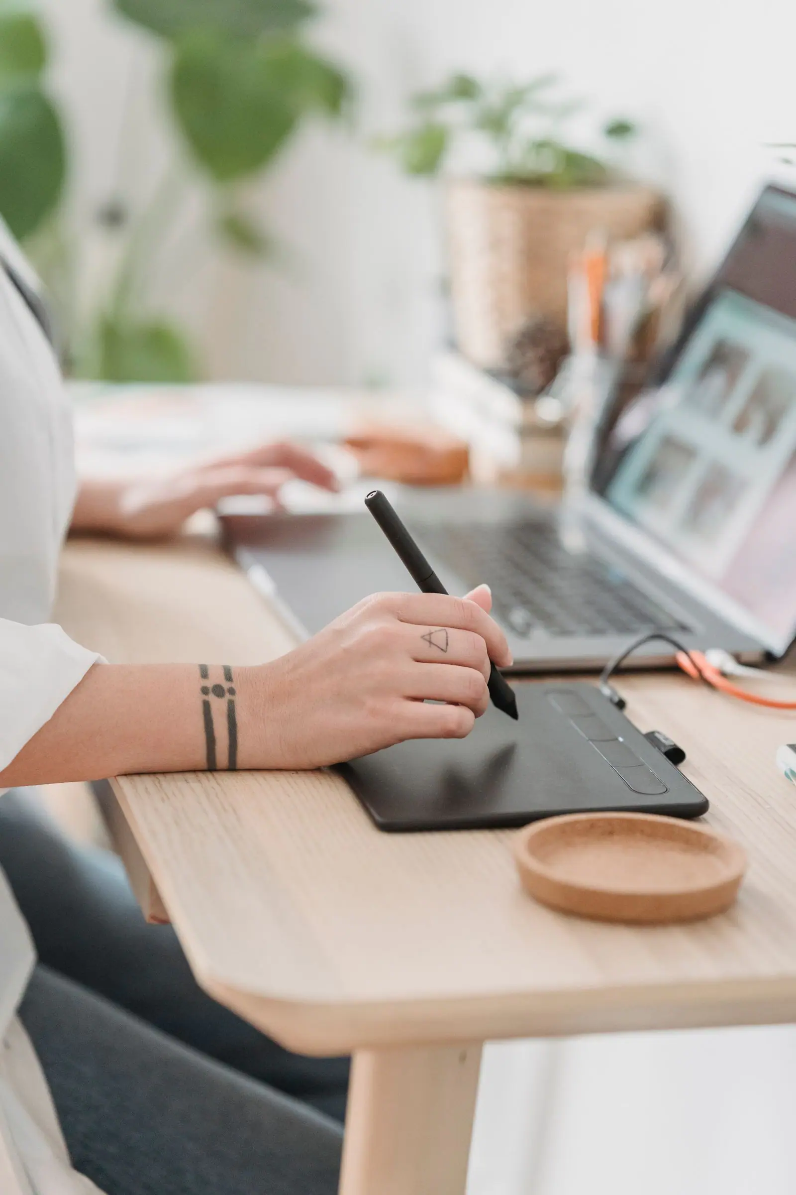 Designer drawing on a graphics tablet next to a laptop